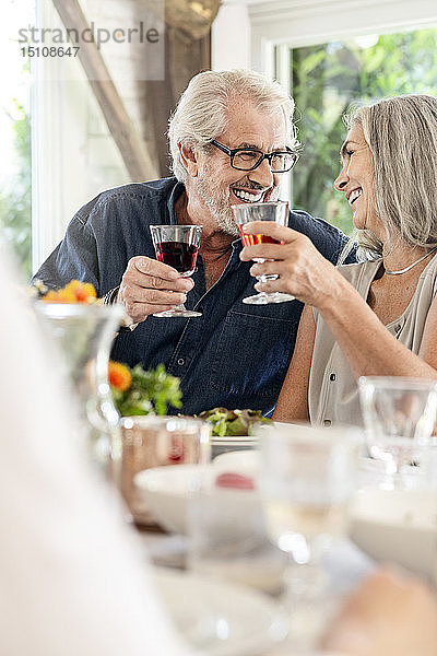 Älteres Ehepaar feiert mit der Familie  klirrende Gläser