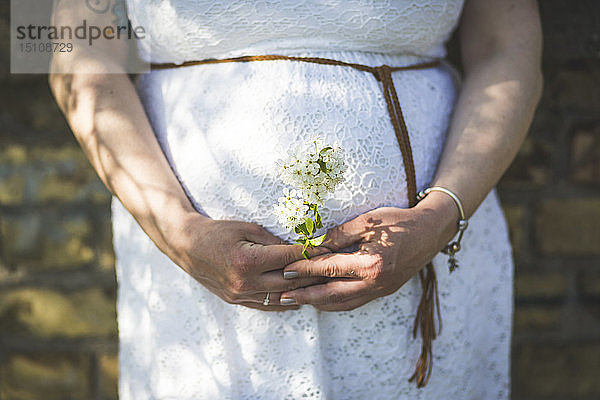 Schwangere Frau hält Blumen  Nahaufnahme