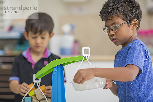 Jungen spielen im Kindergarten mit Spielzeugwaagen