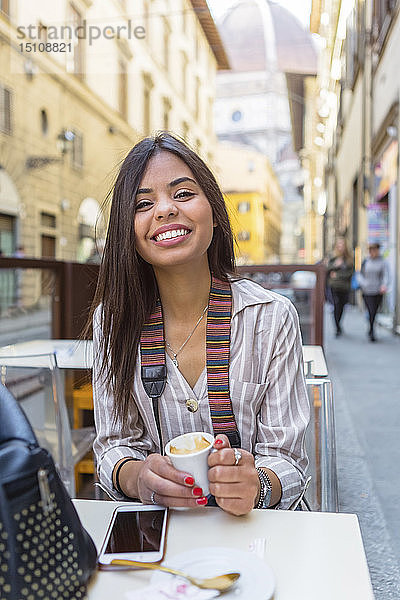 Italien  Florenz  Porträt eines glücklichen jungen Touristen  der im Straßencafé Espresso trinkt