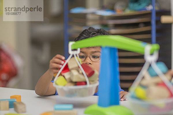 Junge spielt im Kindergarten mit Spielzeugwaagen