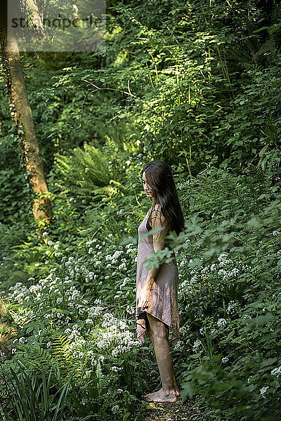 Junge Frau steht auf einem Pfad in einem üppigen Wald  Garrotxa  Spanien