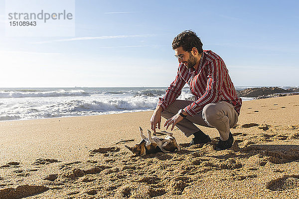 Portugal  Porto  junger Mann spielt mit seinem Hund am Strand