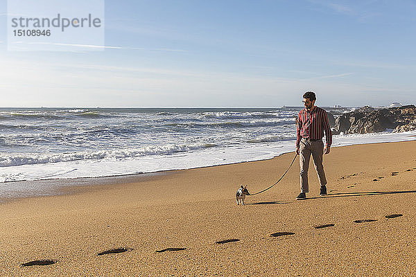 Portugal  Porto  junger Mann  der mit seinem Hund am Strand spazieren geht