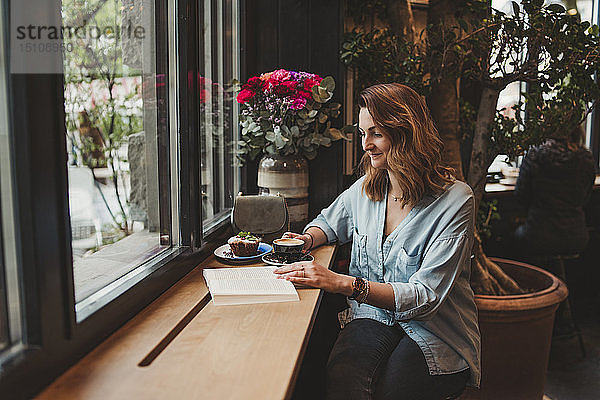 Junge Frau liest ein Buch in einem Cafe