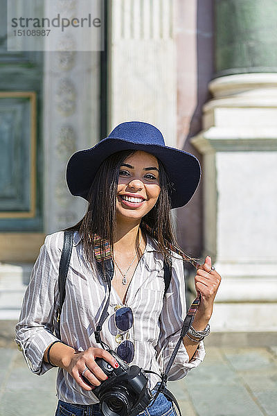 Italien  Florenz  Porträt eines glücklichen jungen Touristen mit Kamera und Sonnenbrille
