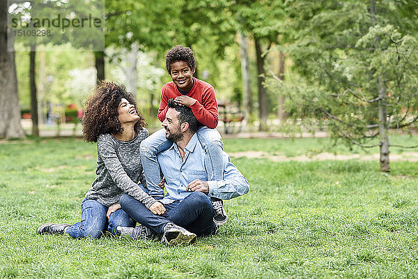Glückliche Familie sitzt auf Gras in einem Park