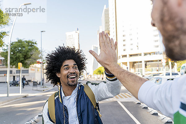 Fröhlicher Gelegenheits-Geschäftsmann high fiving mit Freund in der Stadt  Barcelona  Spanien