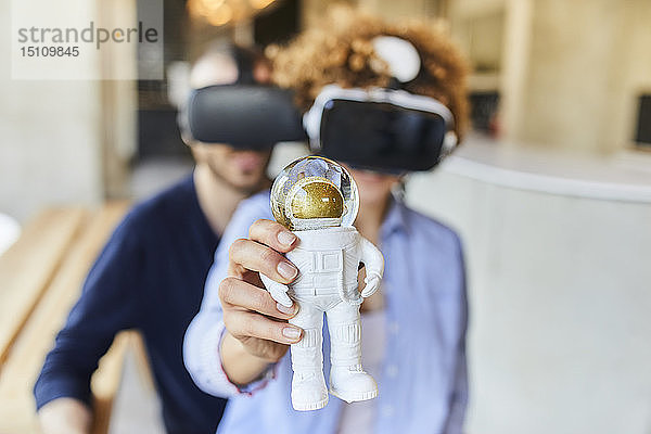 Mann und Frau mit VR-Brille  die eine Astronautenfigur halten