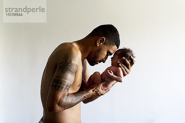 Anhänglicher Vater hält sein nacktes Neugeborenes