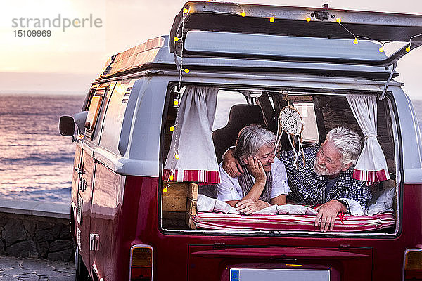 Älteres Ehepaar reist in einem Oldtimer-Van und liegt im Kofferraum