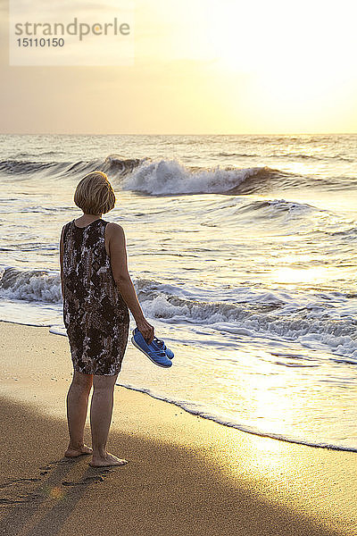 Italien  Sizilien  ältere Frau genießt den Sonnenuntergang am Strand