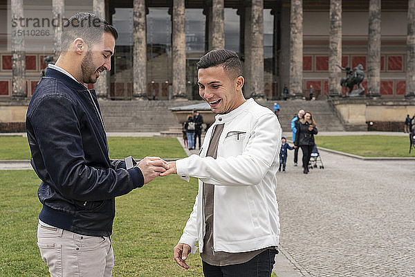 Junger Mann legt seinem glücklichen Freund im Lustgarten einen Ring an  Berlin  Deutschland