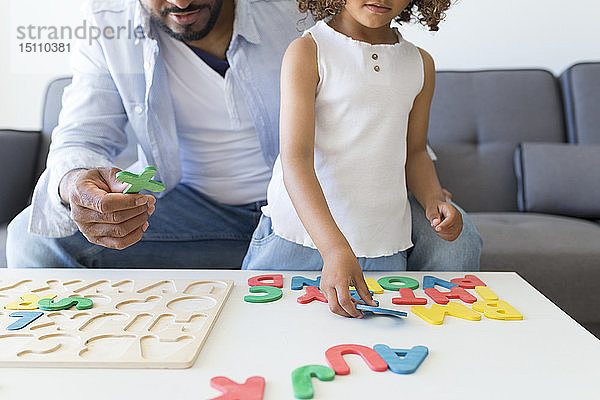 Vater und Tochter spielen zu Hause mit Alphabet-Lernspiel