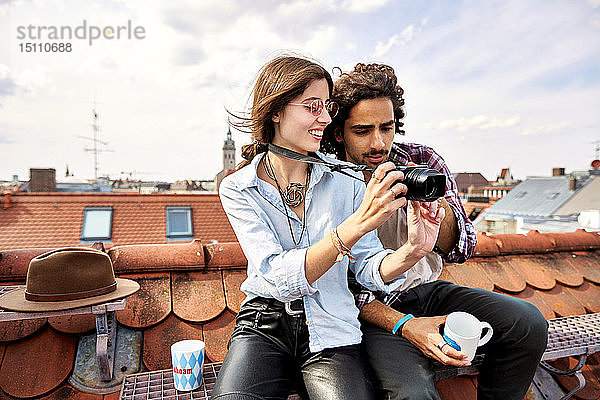 Junges Paar sitzt auf dem Dach und macht Fotos