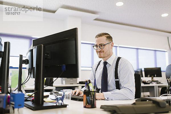 Geschäftsmann mit Computer am Schreibtisch im Büro