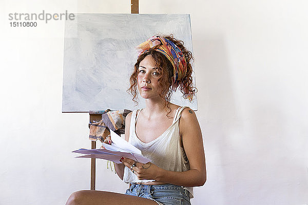 Porträt einer jungen Malerin im Kunstatelier neben einer leeren Leinwand