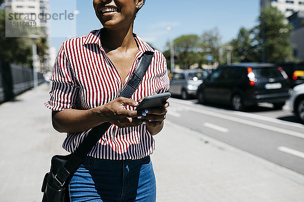 Frau benutzt Smartphone beim Spazierengehen in der Stadt