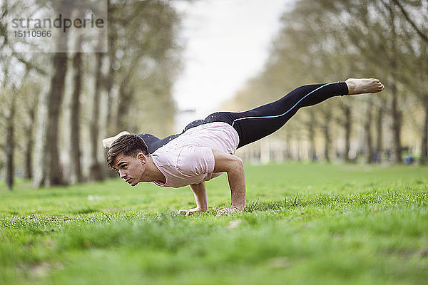 Junger Mann macht Gymnastikakrobatik in einem städtischen Park