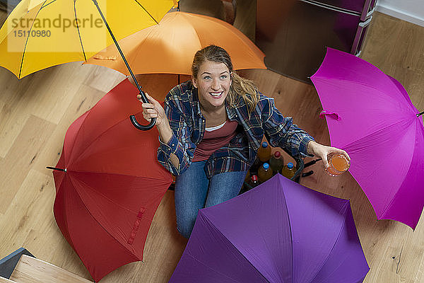 Junge Frau mit Regenschirmen auf dem Boden sitzend