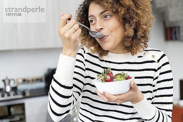Frau isst Erdbeeren zu Hause