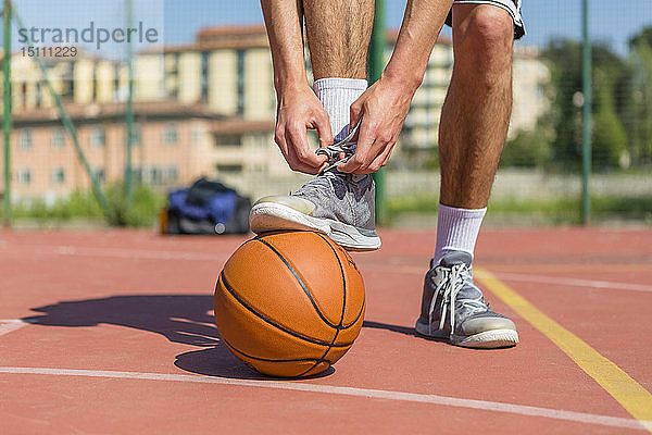 Junger Basketballer beim Schuhbinden