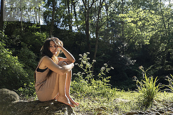 Porträt einer jungen Frau  die auf einem Felsen im Wald sitzt  Garrotxa  Spanien