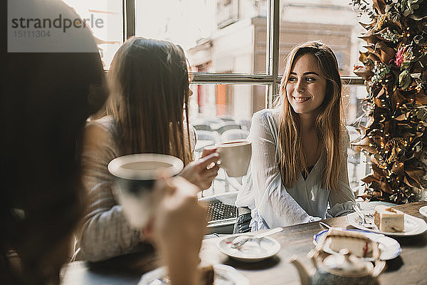 Drei glückliche junge Frauen treffen sich in einem Café