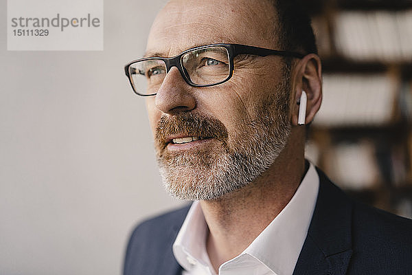 Porträt eines reifen Geschäftsmannes  der mit Bluetooth-Kopfhörern Musik hört
