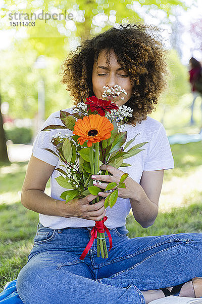 Entspannte Frau im Park riecht nach Blumen