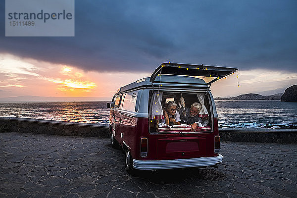 Älteres Ehepaar reist in einem Oldtimer-Van und liegt im Kofferraum