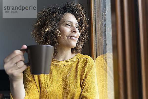 Frau sitzt am Fenster  macht eine Pause  trinkt Kaffee
