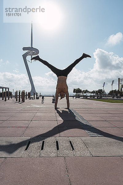 Junger Mann macht einen Handstand im Gegenlicht