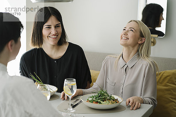Glückliche Freunde essen Salat und Mineralwasser in einem Restaurant