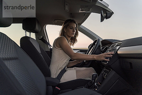 Blonde Fahrerin wählt in ihrem Auto einen Radiosender