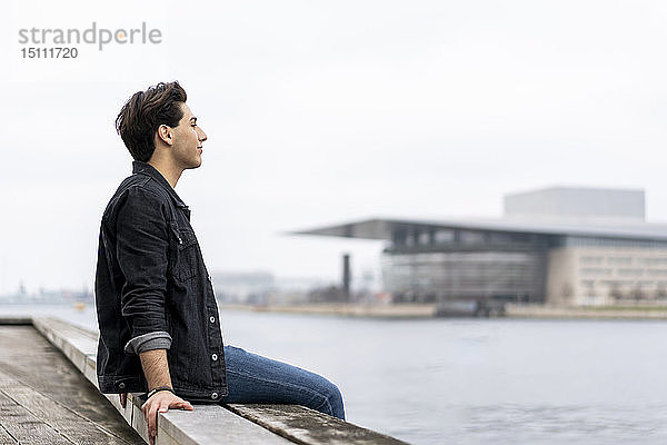 Dänemark  Kopenhagen  junger Mann am Wasser sitzend