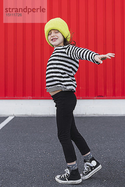 Kleines Mädchen mit gestreiftem Hemd und gelber Mütze beim Balancieren