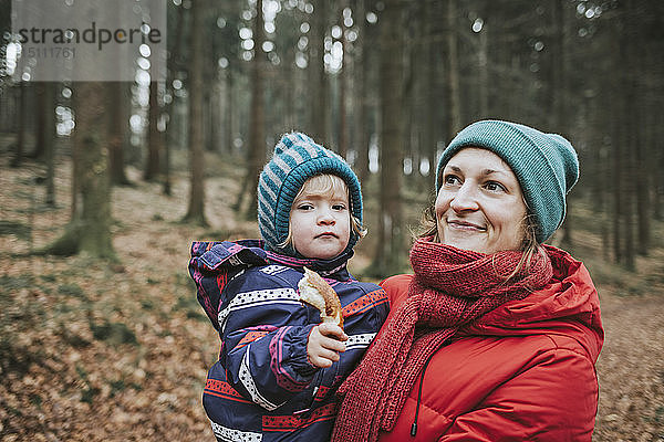 Mutter trägt kleine Tochter im Herbstwald