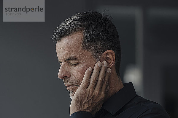 Porträt eines reifen Geschäftsmannes mit Ohrenschmerzen