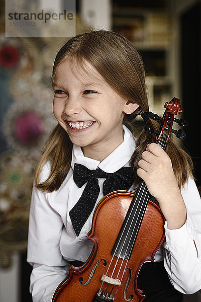 Porträt eines glücklichen Mädchens mit einer Geige zu Hause