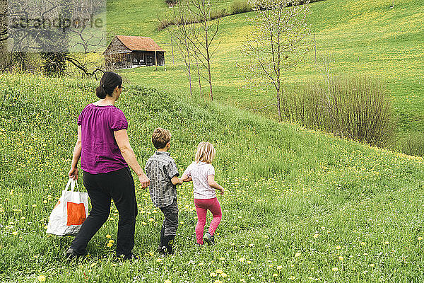 Mutter mit zwei Kindern beim Spaziergang auf der Wiese auf dem Land