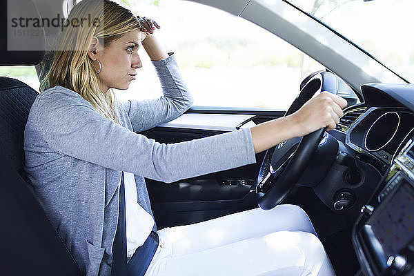 Gestresste junge Geschäftsfrau fährt Auto