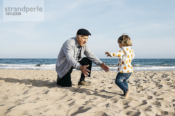 Großvater spielt mit seiner kleinen Enkelin am Strand