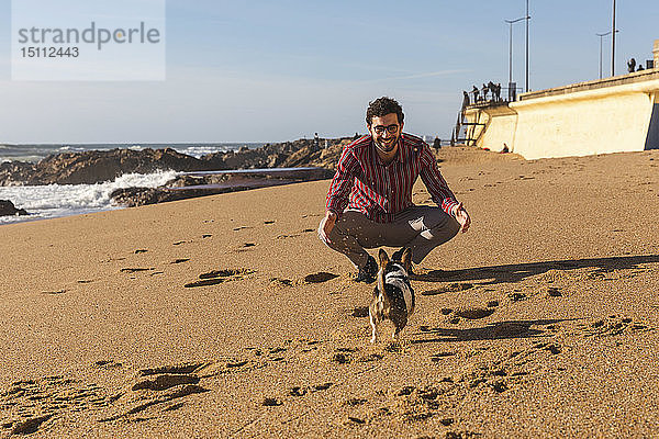Portugal  Porto  junger Mann spielt mit seinem Hund am Strand