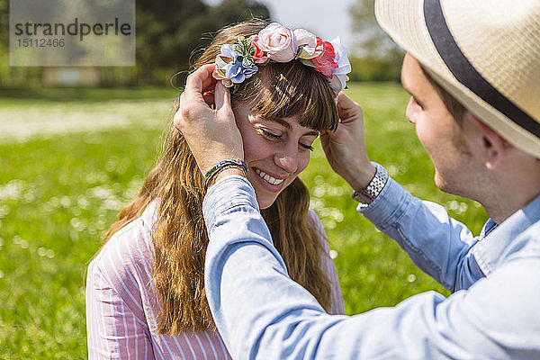 Junger Mann legt seiner Freundin Blumen auf den Kopf