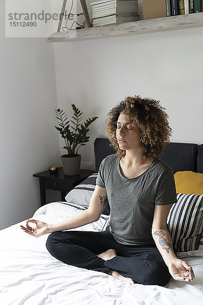 Frau  die Yoga praktiziert  auf dem Bett sitzt  meditiert
