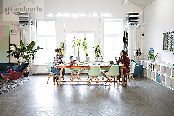 Zwei Frauen arbeiten am Tisch in einem modernen Büro