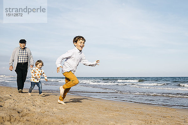 Großvater mit seinen Enkelkindern am Strand spazieren