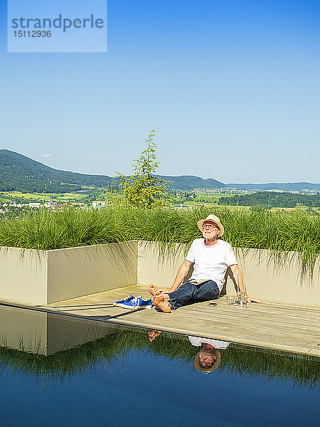 Älterer Mann sitzt am Schwimmbad