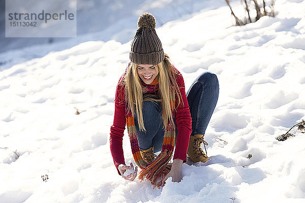 Junge blonde Frau spielt im Winter mit Schnee